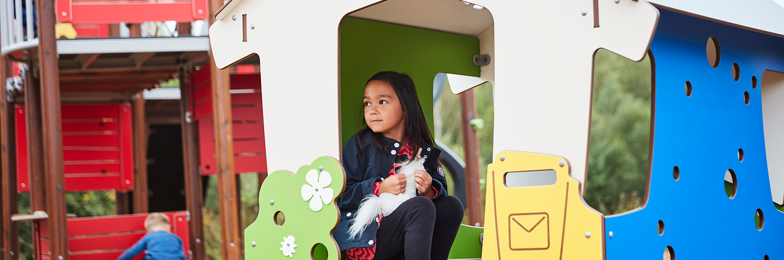 A girl sitting and looking out of a playhouse made out of HPL.